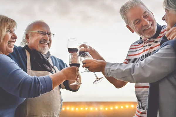 Glückliche Senioren Freunde trinken Rotwein auf der Sonnenterrasse - reife Menschen haben Spaß beim Lachen und gemeinsame Zeit im Freien - Senioren Lebensstil Aktivitätskonzept — Stockfoto