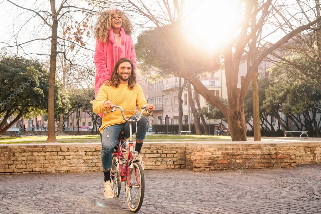 Happy couple riding on bicycle in the city center - Young people having fun outdoor - Millennial generation and youth lifestyle concept