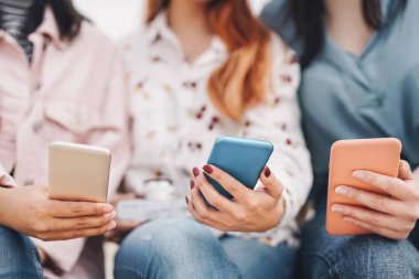 Grup arkadaşları cep telefonlarını açık havada kullanıyor - Milenyum gençleri yeni sosyal medya teknolojisiyle eğleniyor - Gençlik jenerasyonu teknoloji bağımlılığı ve takım pazarlama kavramı