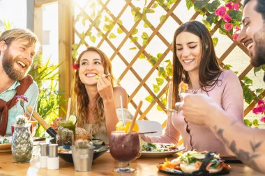 Mutlu arkadaşlar brunch bar restoranında sağlıklı yemekler yiyor - gençler smoothie yiyor ve içiyor - eski bardaki taze meyveler - sağlık eğilimleri yaşam tarzı konsepti