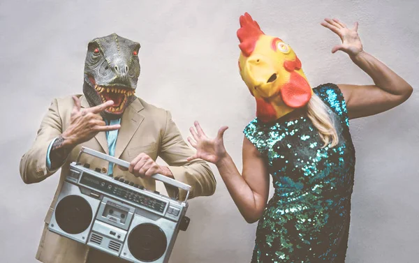Casal sênior louco vestindo frango e t-rex máscara enquanto dança ao ar livre - Pessoas na moda maduros se divertindo celebrando e ouvindo música com boombox - Conceito absurdo de mascarar férias engraçadas — Fotografia de Stock