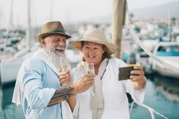 Couple de personnes âgées prenant selfie avec smartphone mobile en vacances en voilier - Happy people having fun celebrate drinking champagne on boat trip - Relationship love and romantic travel dating concept — Photo