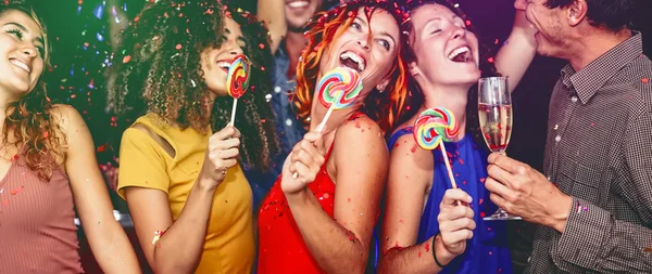 Happy friends celebrating new year eve drinking champagne in nightclub - Young people having fun dancing with lollipops in disco club - Youth culture entertainment lifestyle and nightlife concept — Stock Photo, Image