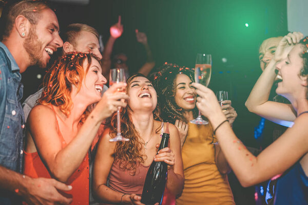 Happy friends doing party drinking champagne in nightclub - Group young people having fun celebrating new year eve holidays together in disco club - Youth culture entertainment lifestyle concept