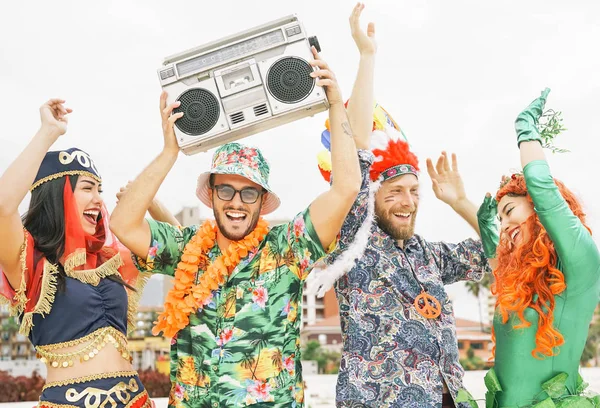 Amigos felices celebrando fiesta de carnaval al aire libre - Jóvenes locos divirtiéndose usando disfraces escuchando música con estéreo de boombox vintage - Concepto de estilo de vida de cultura de vacaciones juveniles — Foto de Stock