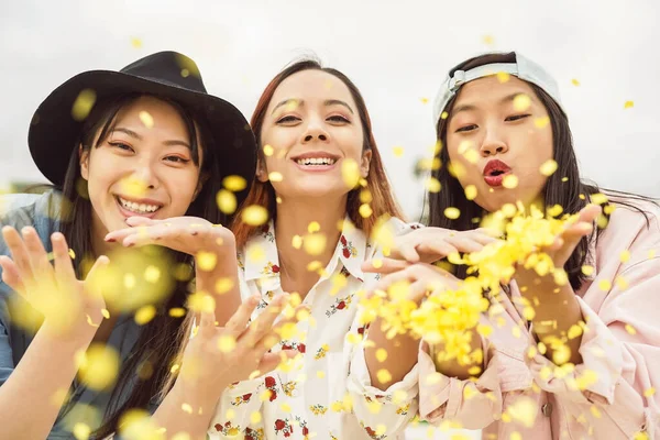 Felices amigos asiáticos divirtiéndose lanzando confeti al aire libre - Gente joven de moda celebrando el evento del festival de carnaval - Fiesta de entretenimiento y vacaciones juveniles concepto de estilo de vida — Foto de Stock