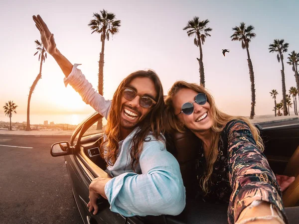 Pareja joven feliz haciendo viaje por carretera en la ciudad tropical - Viajar personas de moda que se divierten conduciendo en coche convertible descubriendo nuevos lugares - Relación y concepto de estilo de vida de vacaciones juveniles — Foto de Stock