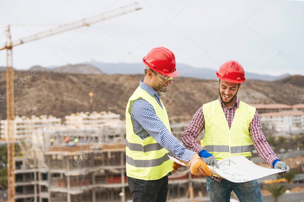 Work engineers discussing about new building area - Young builders reading the project in the construction site - Carpentry teamwork engineering concept