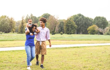Mutlu Afrikalı aile parkında eğleniyor - anne ve baba kızlarıyla birlikte güneşli hafta sonu birlikte eğleniyorlar - ebeveynler birbirini seviyor ve anneler günü konsepti