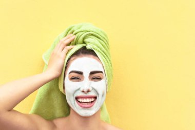 Mutlu kız yüz kilinden maske takıyor - genç kadın cilt bakımına gidiyor - güzellik temizliği günü ve kozmetoloji ürünleri konsepti