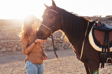 Genç çiftçi ahırın içinde atlarla eğleniyor - Çiftlikte hayvanlarla oynayan mutlu kız - İnsan ve hayvan ilişkileri kavramı