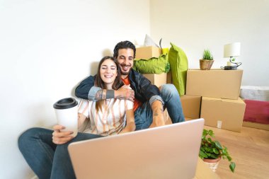 Yeni eve ilk taşınan mutlu genç çift - bir sonraki emlak evinde bilgisayar kullanarak eğlenen erkek ve kadın - Apartman gününü ve insanların yaşam tarzı ilişki kavramını değiştirin