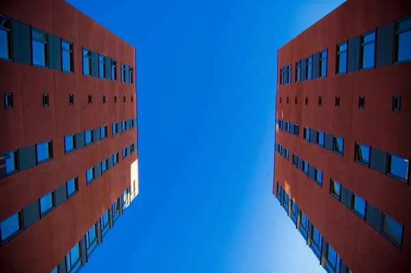 Two houses in front of each other. Photo take from low angle; two red suburban buildings facing eachother with blue sky in background. Suburban and building concept.