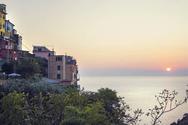 Belo pôr do sol com montanhas, oceano / mar e arredores exuberantes. Ambiente mediterrânico. Bela profundidade de imagem e luzes harmônicas. Também mostrando a aldeia oceânica. Tema de férias Imagens De Bancos De Imagens Sem Royalties