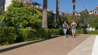 Genç kadınlar mekik çekiyorlar, koşuyorlar, bahçede egzersiz yapıyorlar. Birlikte egzersiz yapıyorlar. Evde kal. Covid 19