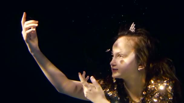 Little girl in a dark water of pool is drawning to the light her face and hands, crown of princess is on her head — Stock Footage Little girl in a dark water of pool is drawning to the light her face and hands, crown of princess is on her head Royalty Free Stock Video