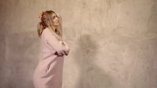 Slender charming blonde girl is dancing against the wall in a warm cardigan — Stock Footage Slender charming blonde girl is dancing against the wall in a warm cardigan Stock Video
