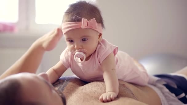 cute baby girl with baby pacifier is lying on belly and chest of her