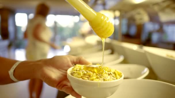 A close shot at the hands of a woman who pours sweet flakes for breakfast with honey — Stock Footage A close shot at the hands of a woman who pours sweet flakes for breakfast with honey Stock Video