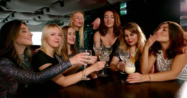 women with drinks celebrate holiday in modern nightclub