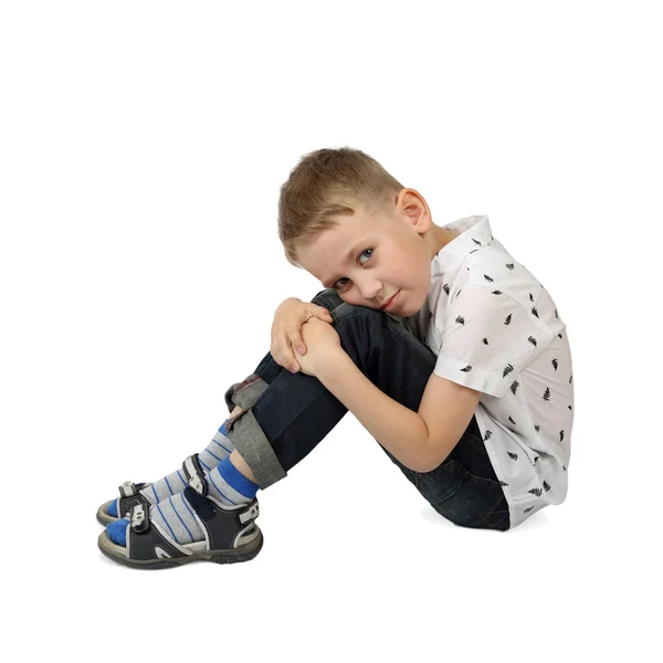 Sad little boy sits on floor hugging his knees — Stock Photo, Image