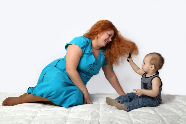 Happy redhead woman sits on blanket playing with her little son — Stock Photo, Image