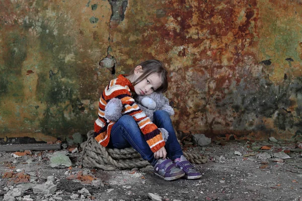 Kleines Mädchen sitzt mit Teddybär in der Hand im Keller — Stockfoto