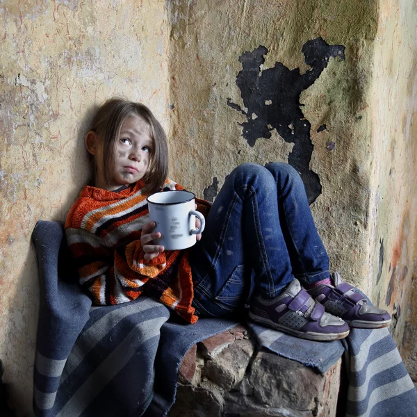 Kleines Mädchen sitzt mit Becher in der Hand im Keller — Stockfoto