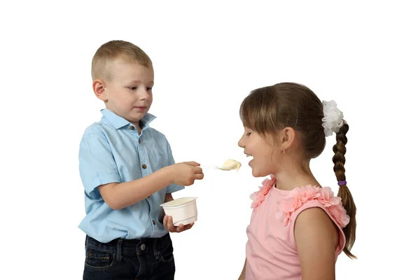 Pequeño niño alimenta a chica por yogur con cuchara se centran en la chica y spo — Foto de Stock