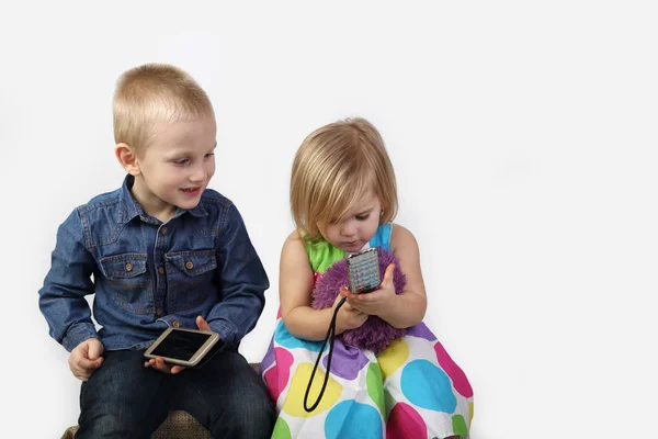 Маленький хлопчик і дівчинка з мобільними телефонами на сірому — стокове фото