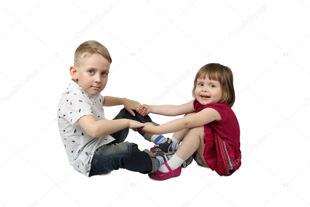 Little boy and girl sit on floor and hold each others hands