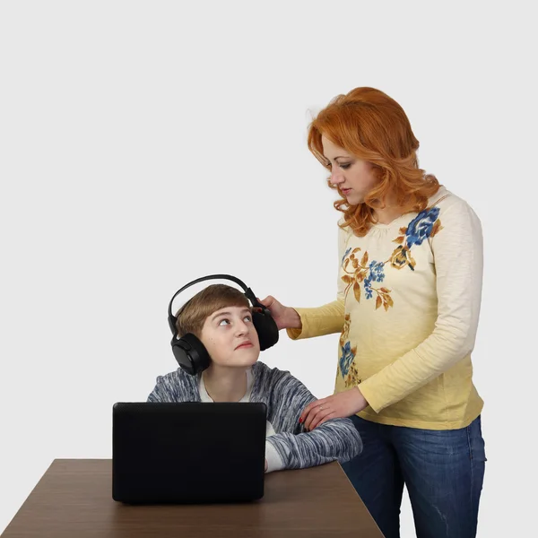 Mother tries to distract son in headphones from computer — ストック写真