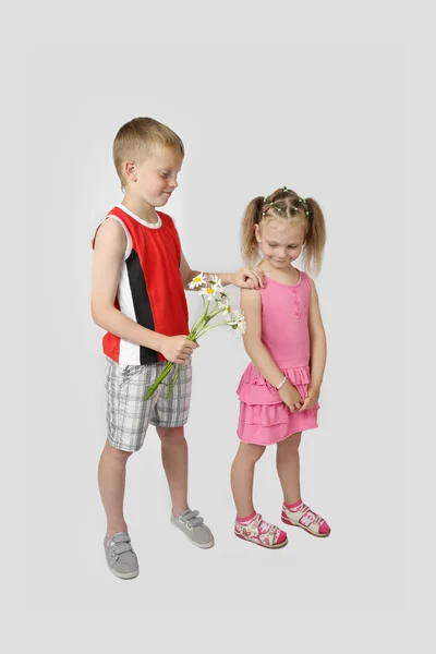 Boy gives girl bouquet of daisies on gray — Stock Photo, Image