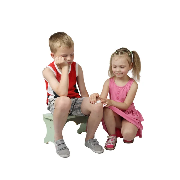 Маленька дівчинка накладає пляму на коліно старшого хлопчика — стокове фото