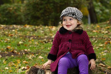 Küçük kız ağaç kütüğü üzerinde oturur