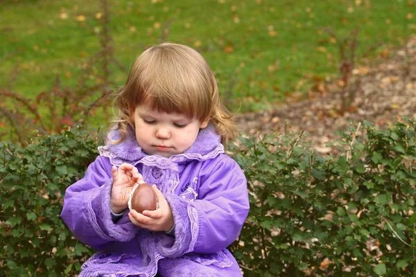 Маленькая девочка чистит шоколадное яйцо — стоковое фото