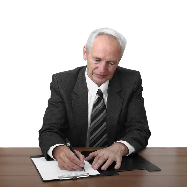 Senior man zit aan tafel en document schrijft — Stockfoto