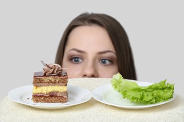 Genç kadın pasta ve marul arasında seçer