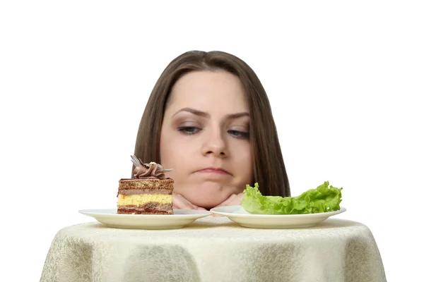 Young woman chooses between cake and lettuce — Stock Photo, Image