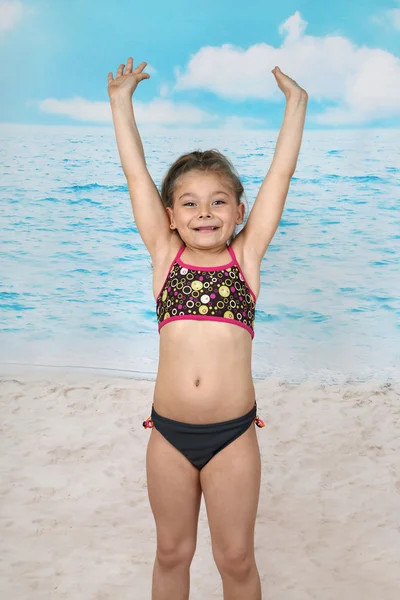 Söpö pieni tyttö hyppää rannalla — kuvapankkivalokuva