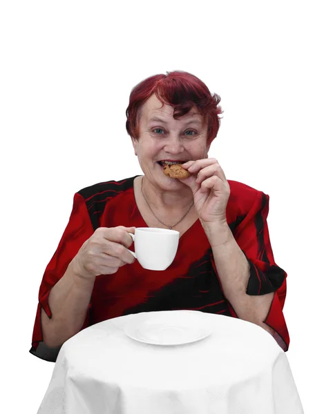 Senior woman eats cookie — Stockfoto