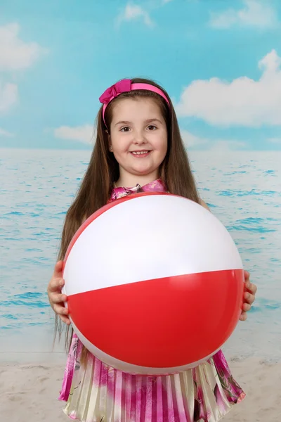 Опухшая маленькая девочка на пляже с большим мячом в руках — стоковое фото