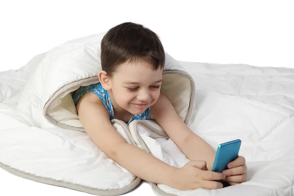 Маленький хлопчик під ковдрою грає зі смартфоном — стокове фото