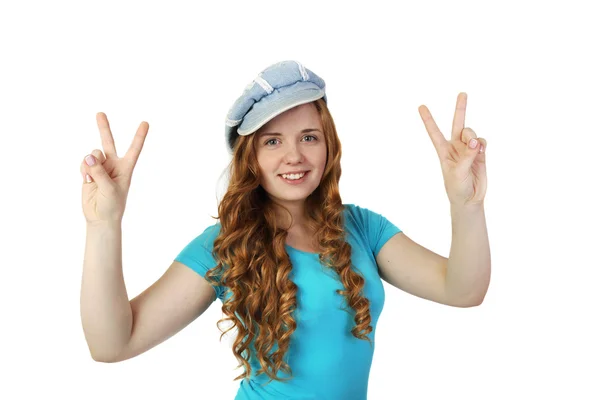 Young pretty redhead girl in cap shows victory gesture — Stock Photo, Image