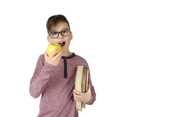 Хлопчик зі стопкою книг під рукою їсть яблуко — стокове фото