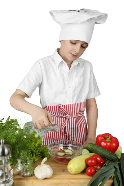 Little boy cook adds spice to salad — Stock Photo, Image
