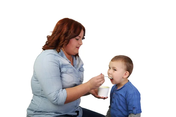 Woman girl feeds little boy — Stock Photo, Image