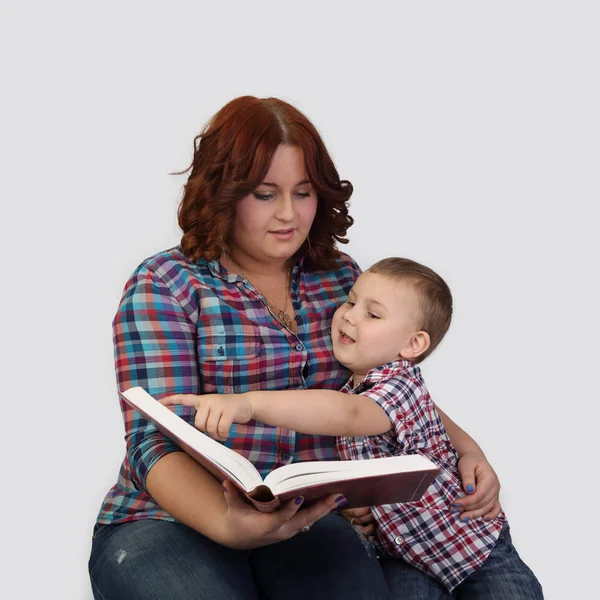 Red haired woman sits together with little boy reading a big boo — Stock Photo, Image