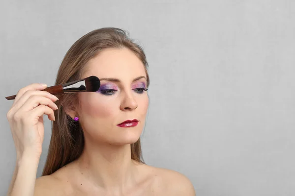 Junge hübsche Frau zeigt Make-up — Stockfoto