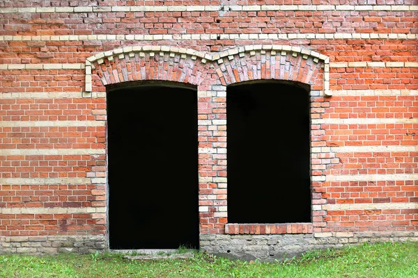 Brown brick wall with dark door and window holes — Stock Photo, Image